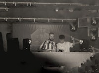 two djs on stage in a dark room